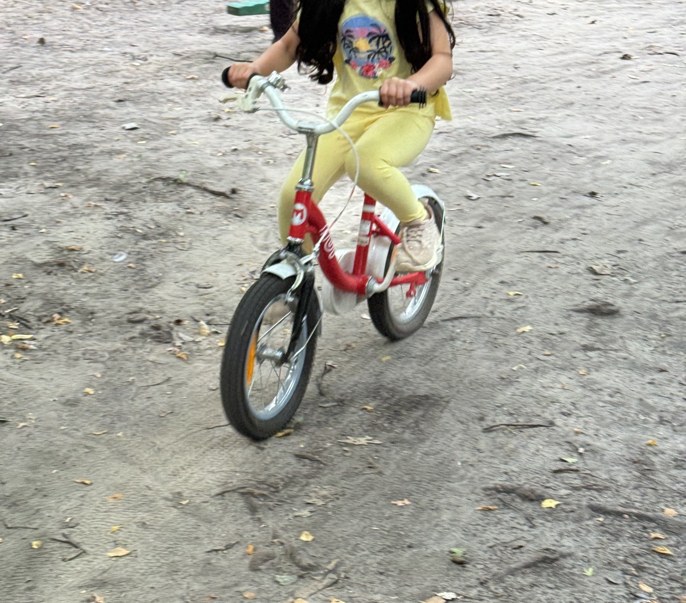 Kind fährt Fahrrad auf den Wegen im Garten der Penthaus Kita