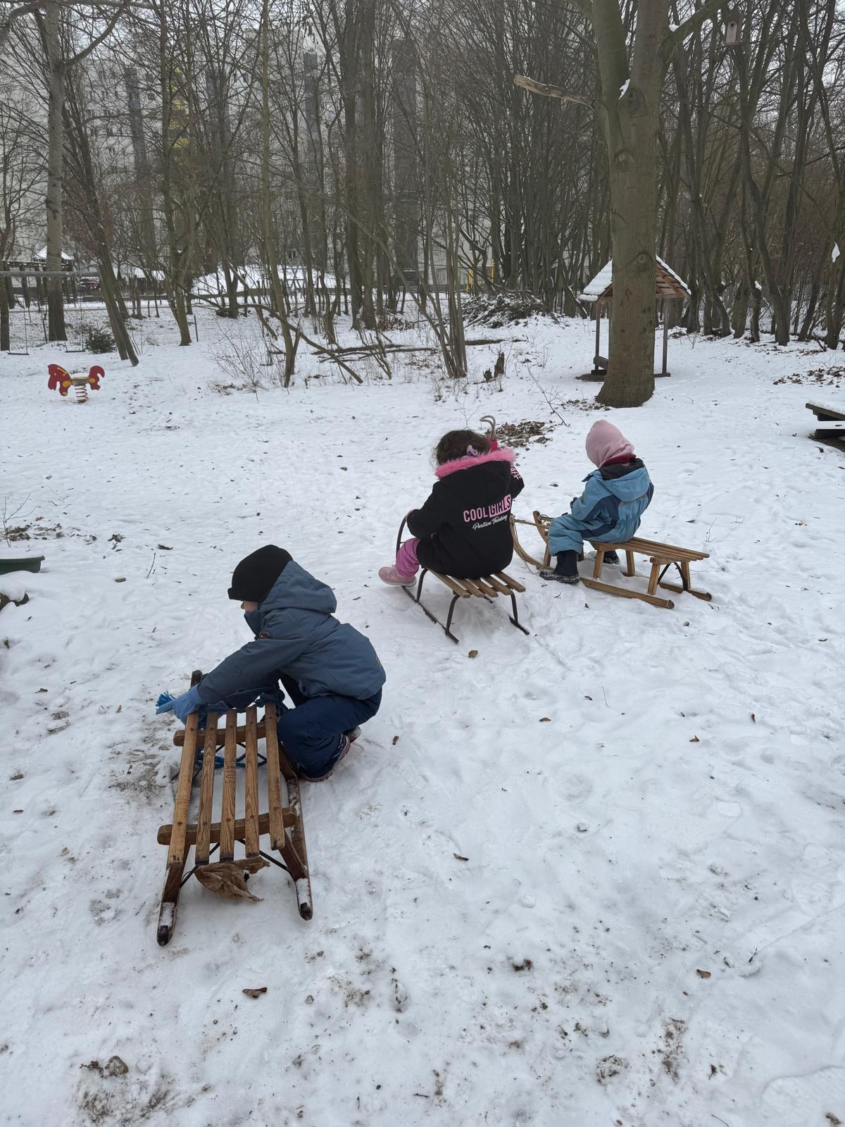 Kinder rodeln im verschneiten Kita-Garten