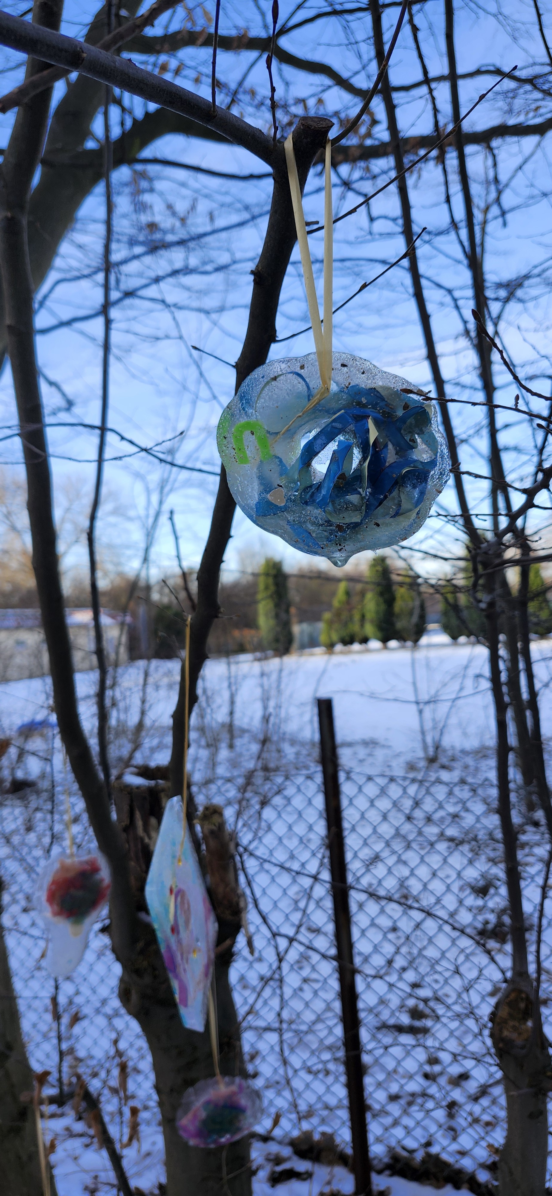 Fertiger Eis-Anh&auml;nger mit blauen B&auml;ndern h&auml;ngt im Baum