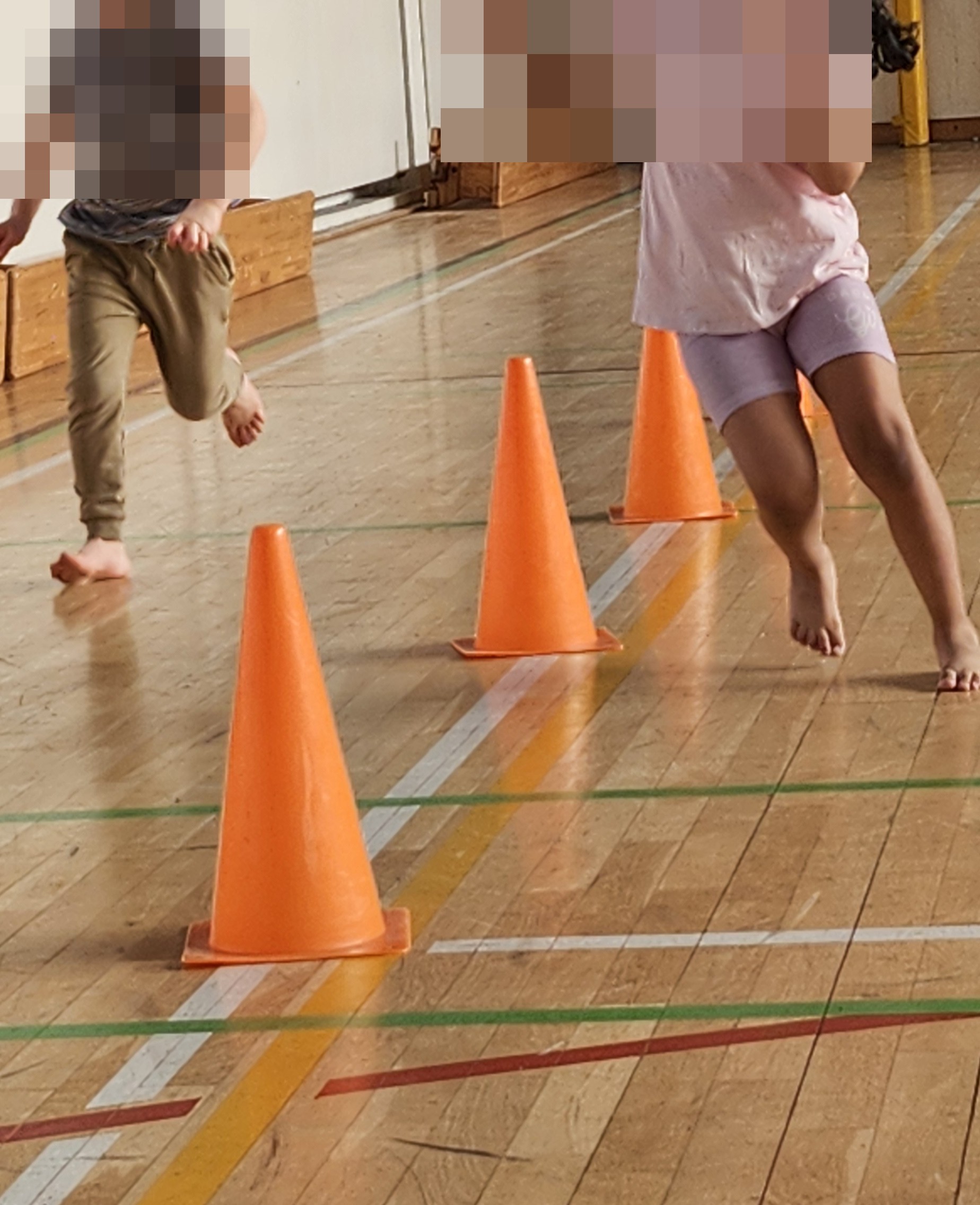 Kinder laufen einen Parcours mit H&uuml;tchen in der Turnhalle