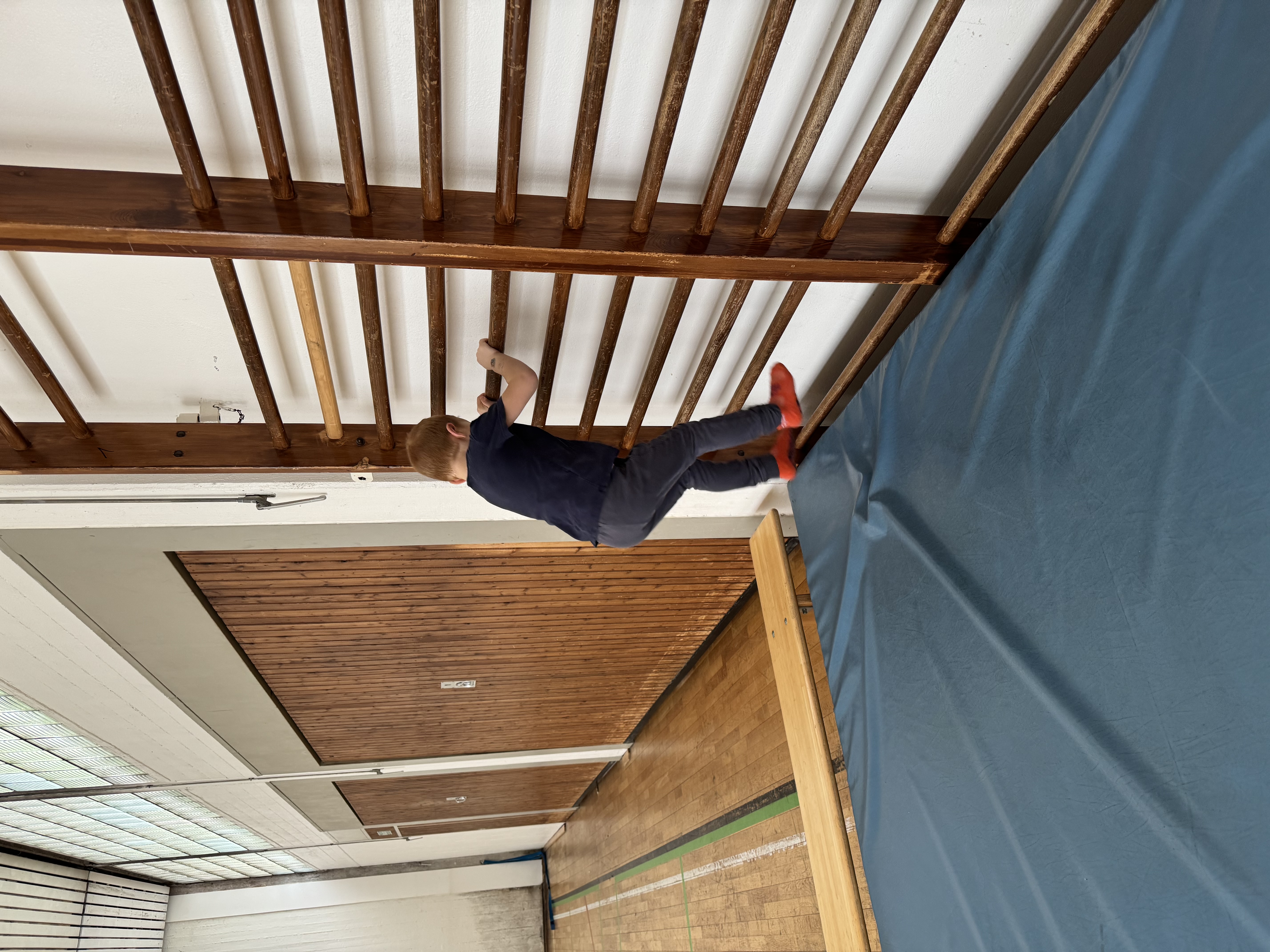 Kind klettert an der Sprossenwand der Turnhalle
