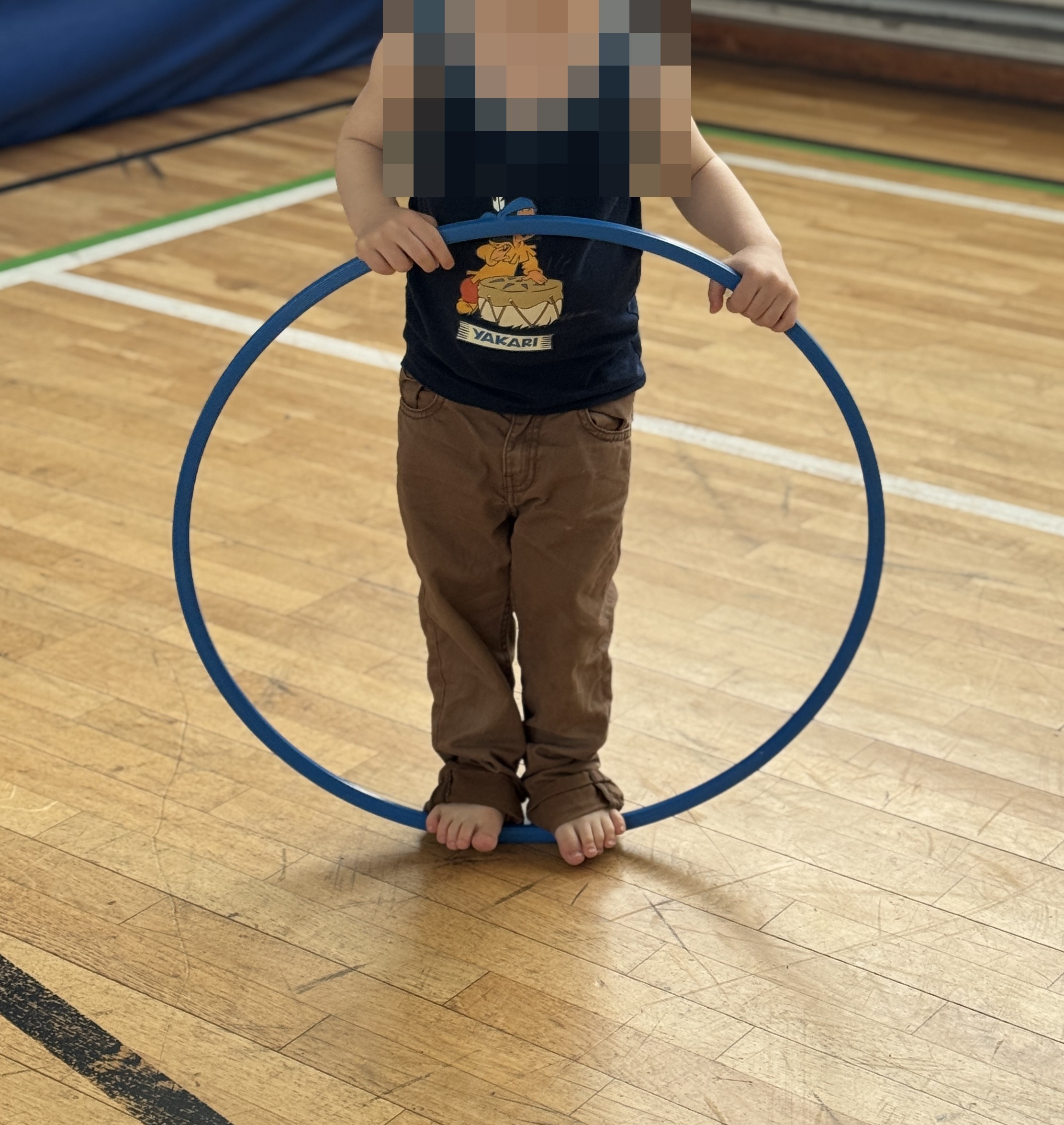 Kind spielt mit einem Gymnastikreifen in der Turnhalle